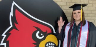 Christel Blocker stands in front of a Cardinal head in her cap and gown.