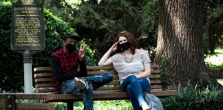 Masked students talk on a bench