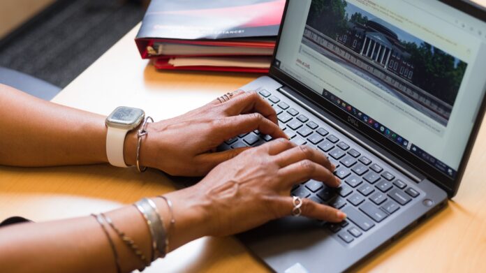 Employee typing on laptop in a UofL office Virtual program helps faculty reach goals.
