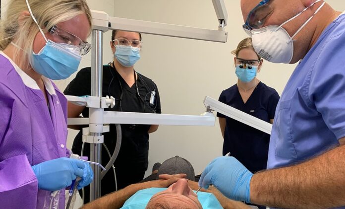 WKCTC Dental assisting program student Lakin Reed (left) assists Dr. Gregory Lord (right) with a recent procedure as UofL dental students Virginia Dunlap (left) and Allison Reed (right) observe.