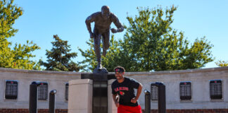 Terry Smith, Jr. posing with Lenny Lyles Statue.