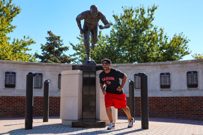 Terry Smith, Jr. posing with Lenny Lyles Statue.