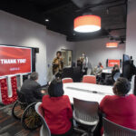 Cherie Dawson-Edwards speaks at a ceremony honoring lab renovation donor Sam Lord, far left at table, with President Neeli Bendapudi.