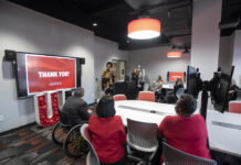 Cherie Dawson-Edwards speaks at a ceremony honoring lab renovation donor Sam Lord, far left at table, with President Neeli Bendapudi.