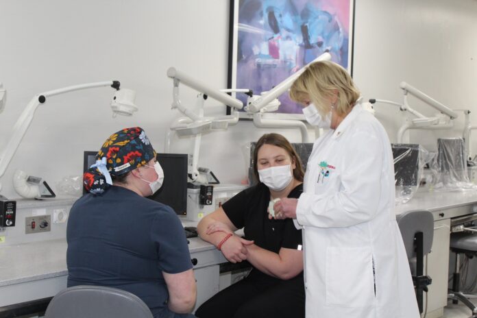 Two student officers of the American Association for Women Dentists talk with P. Gay Baughman.