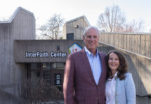 A man and woman stand in front of the concrete Interfaith Center building on the UofL campus