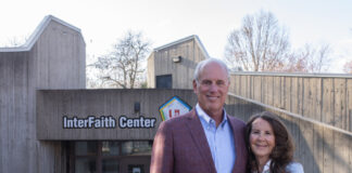 A man and woman stand in front of the concrete Interfaith Center building on the UofL campus