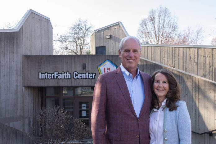 A man and woman stand in front of the concrete Interfaith Center building on the UofL campus