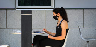 Student studies outside while wearing a mask