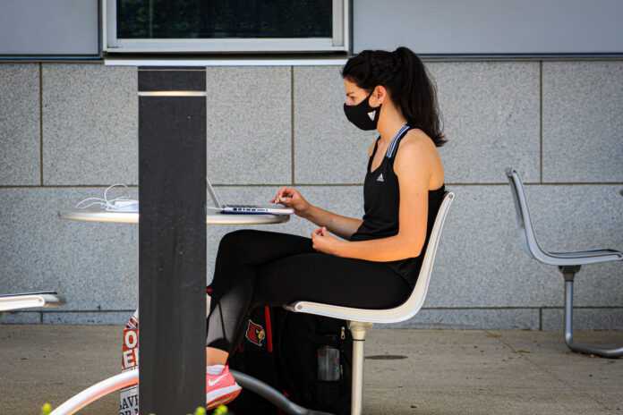 Student studies outside while wearing a mask