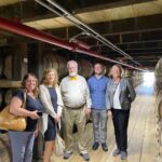 Manuela Perri, Julijana Curcic, Bob Hausladen, Alex Bryant and Virginia Denny of the UofL College of Business executive education program in a barrel house at Jim Beam Distillery.