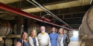 Manuela Perri, Julijana Curcic, Bob Hausladen, Alex Bryant and Virginia Denny of the UofL College of Business executive education program in a barrel house at Jim Beam Distillery.