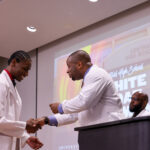 UofL School of Medicine assistant professor Edward Miller, MD, presents a pin to one of the Central High School students at the white coat ceremony