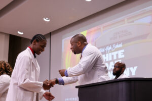 UofL School of Medicine assistant professor Edward Miller, MD, presents a pin to one of the Central High School students at the white coat ceremony