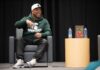 Eric Thomas speaking, seating on stage, wearing ball cap and Michigan State Spartans hoodie