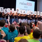 raiseRED participants holding up numbers to reveal the total raised, $551,954.66.