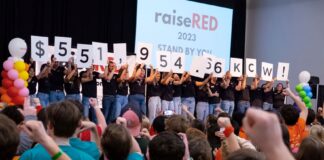 raiseRED participants holding up numbers to reveal the total raised, $551,954.66.