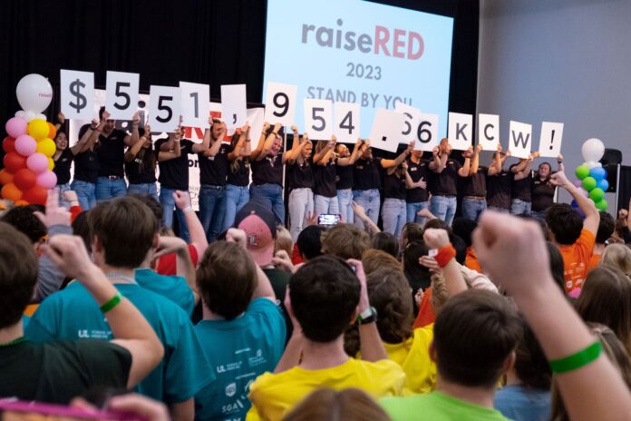 raiseRED participants holding up numbers to reveal the total raised, $551,954.66.