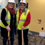 Carissa Gentry and Kristen Roy in hard hats with sledge hammers