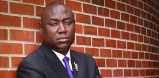 Benjamin Crump, arms crossed in front of him, standing with his back against a brick wall