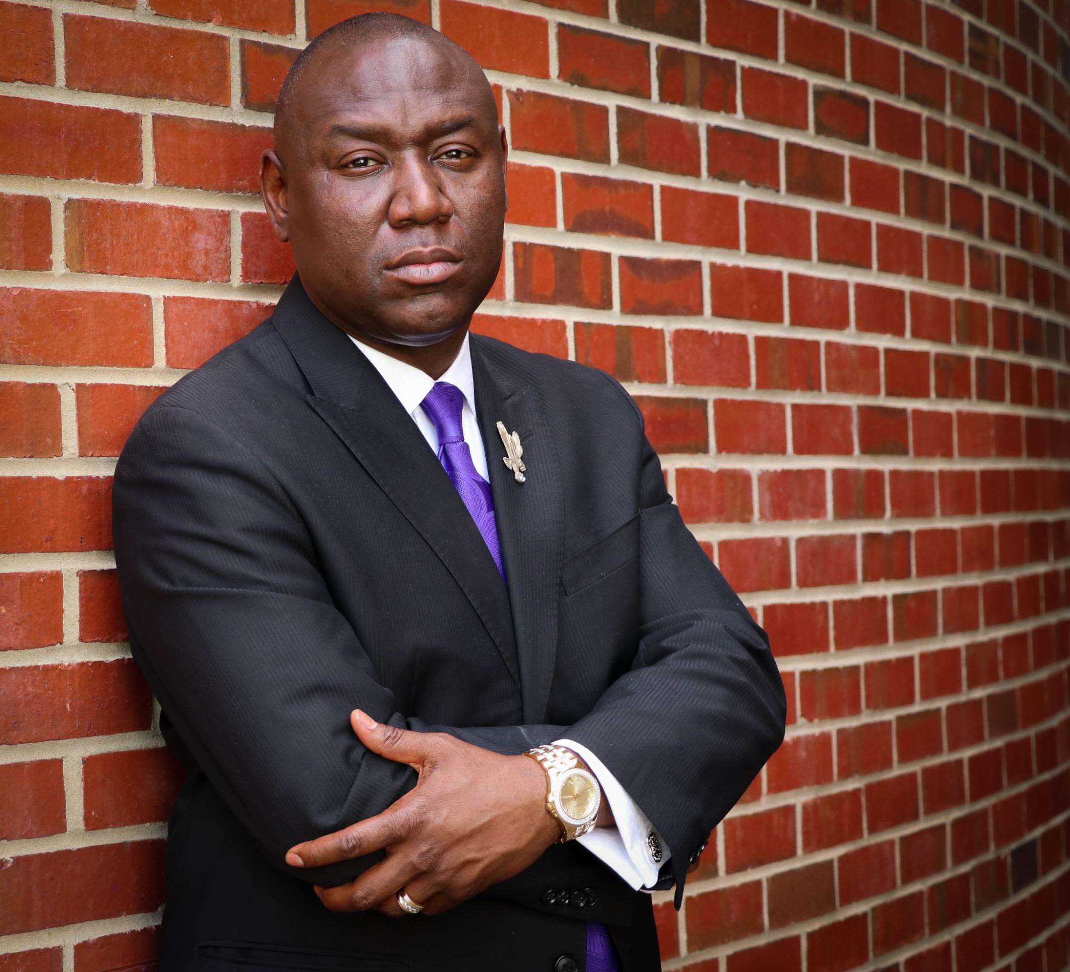 Benjamin Crump, arms crossed in front of him, standing with his back against a brick wall