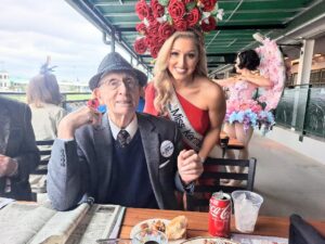 photo of older gentleman sitting at a table with a female pageant winner