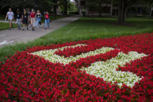 Students walk in the background with flowers in bloom.