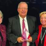 The University of Louisville Board of Trustees recognized John Smith (center) for his more than 36 years of service to the university. Smith, who recently retired as UofL's assistant director of intramural and recreational sports, served on UofL's Staff Senate (chair, 2018-2023) and as the staff representative on the Board of Trustees. Pictured with Smith are UofL President Kim Schatzel, left, and Board Chair Mary Nixon.