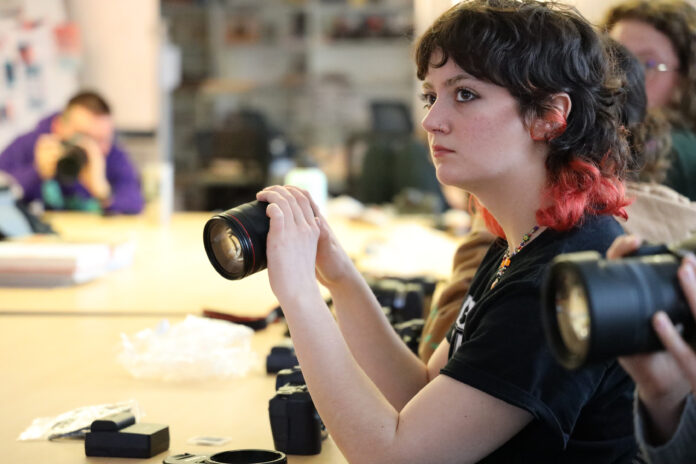 Student holds a Canon camera.