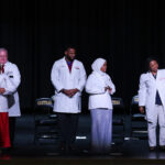 UofL doctors Jeffrey Bumpous, interim dean of the UofL School of Medicine, Edward Miller and Tanya Franklin (back row, l. to r.) placed white coats on the shoulders of Central High School juniors participating in the Pre-Medical Magnet Program. UofL Health photo.
