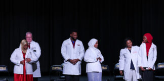 UofL doctors Jeffrey Bumpous, interim dean of the UofL School of Medicine, Edward Miller and Tanya Franklin (back row, l. to r.) placed white coats on the shoulders of Central High School juniors participating in the Pre-Medical Magnet Program. UofL Health photo.