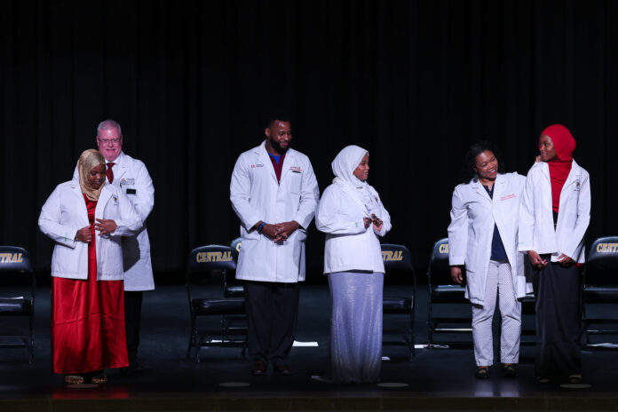 UofL doctors Jeffrey Bumpous, interim dean of the UofL School of Medicine, Edward Miller and Tanya Franklin (back row, l. to r.) placed white coats on the shoulders of Central High School juniors participating in the Pre-Medical Magnet Program. UofL Health photo.
