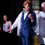 Jeffrey Bumpous, interim dean of the UofL School of Medicine, right, placed a white coat on the shoulders of a Central High School junior participating in the Pre-Medical Magnet Program. UofL Health photo.
