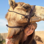 Isabella Leslie stands next to a camel in Dubai.