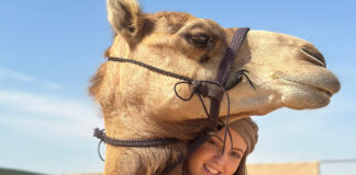 Isabella Leslie stands next to a camel in Dubai.