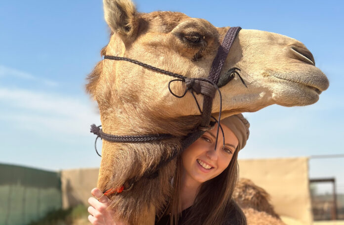 Isabella Leslie stands next to a camel in Dubai.