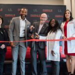 Several people cut a red ribbon with large scissors.
