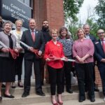 A group of UofL leaders, faculty and staff take part in a ribbon cutting ceremony.