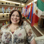 Tiffany Martin smiles beside flags of the world