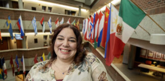 Tiffany Martin smiles beside flags of the world