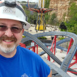 A man stands next to a roller coaster track