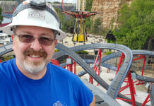 A man stands next to a roller coaster track