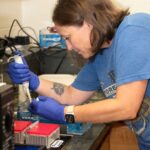 A woman loads fluids into a test tube in a lab.