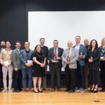 Group of people holding glass awards on stage