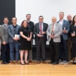 Group of people holding glass awards on stage