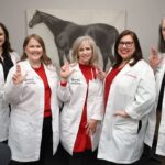 Staff and faculty from the School of Nursing pose in front of a horse statue at the Kentucky Racing Health Services Clinic.