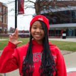 Girl in red sweatshirt holding up the 'L' sign