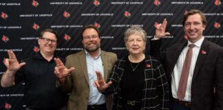 Four people in front of UofL backdrop