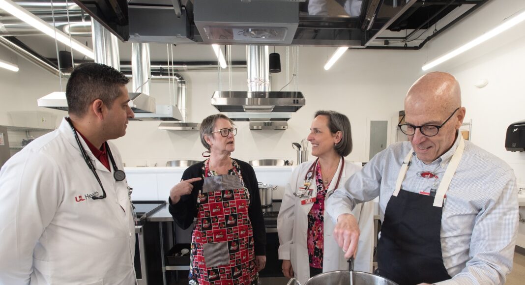 Four adults talking in a commercial-style kitchen