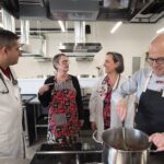 Four adults talking in a commercial-style kitchen